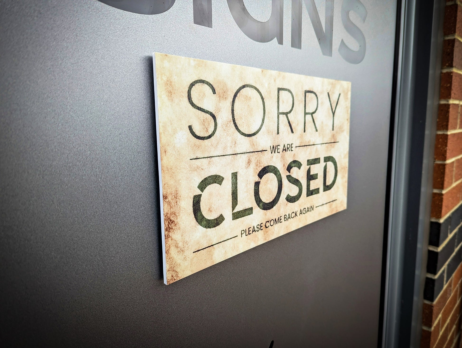 Closed sign fixed to glass door. Sign is changeable with velcro pads to the rear.