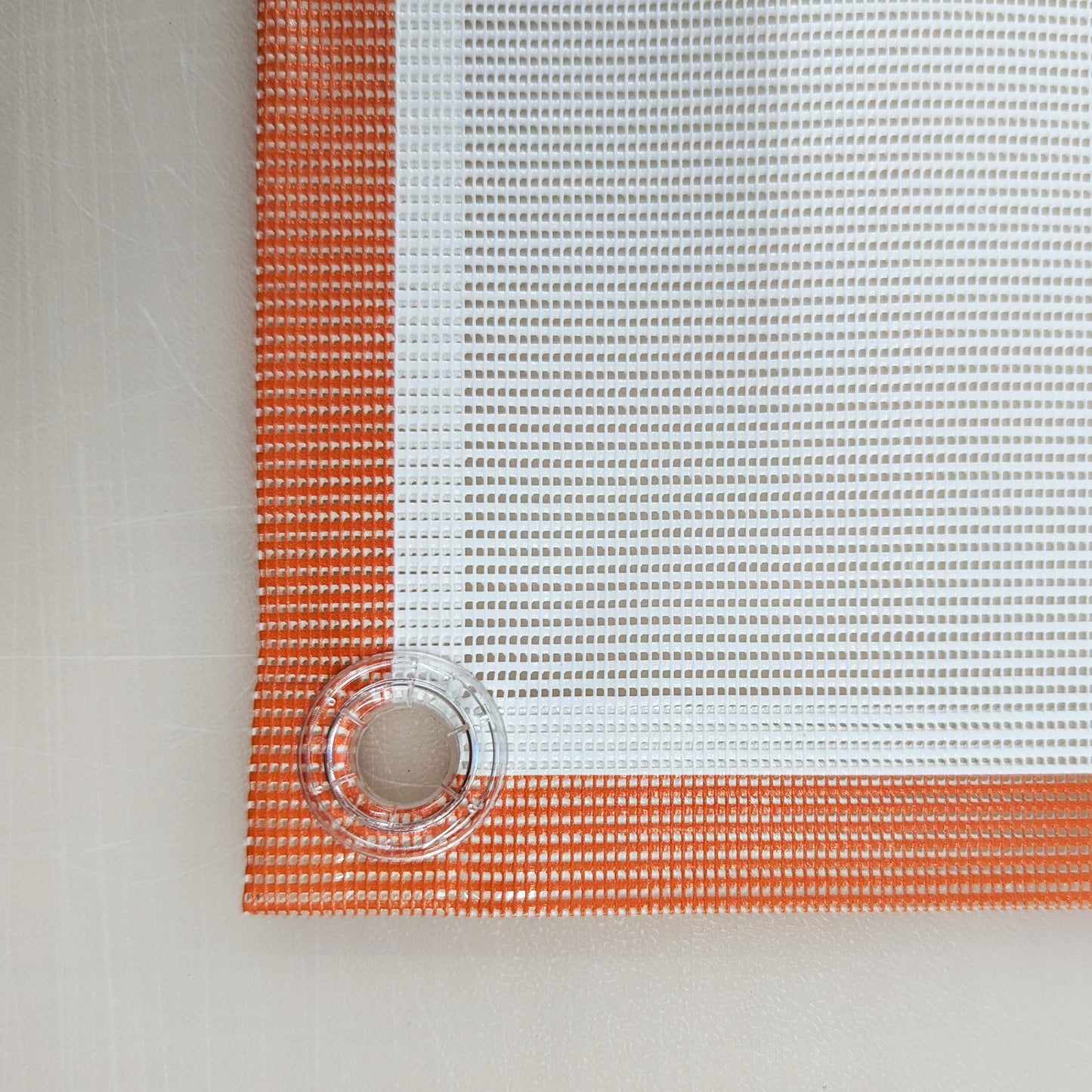 Close-up front image of a printed mesh banner that has been hemmed with clear eyelets.