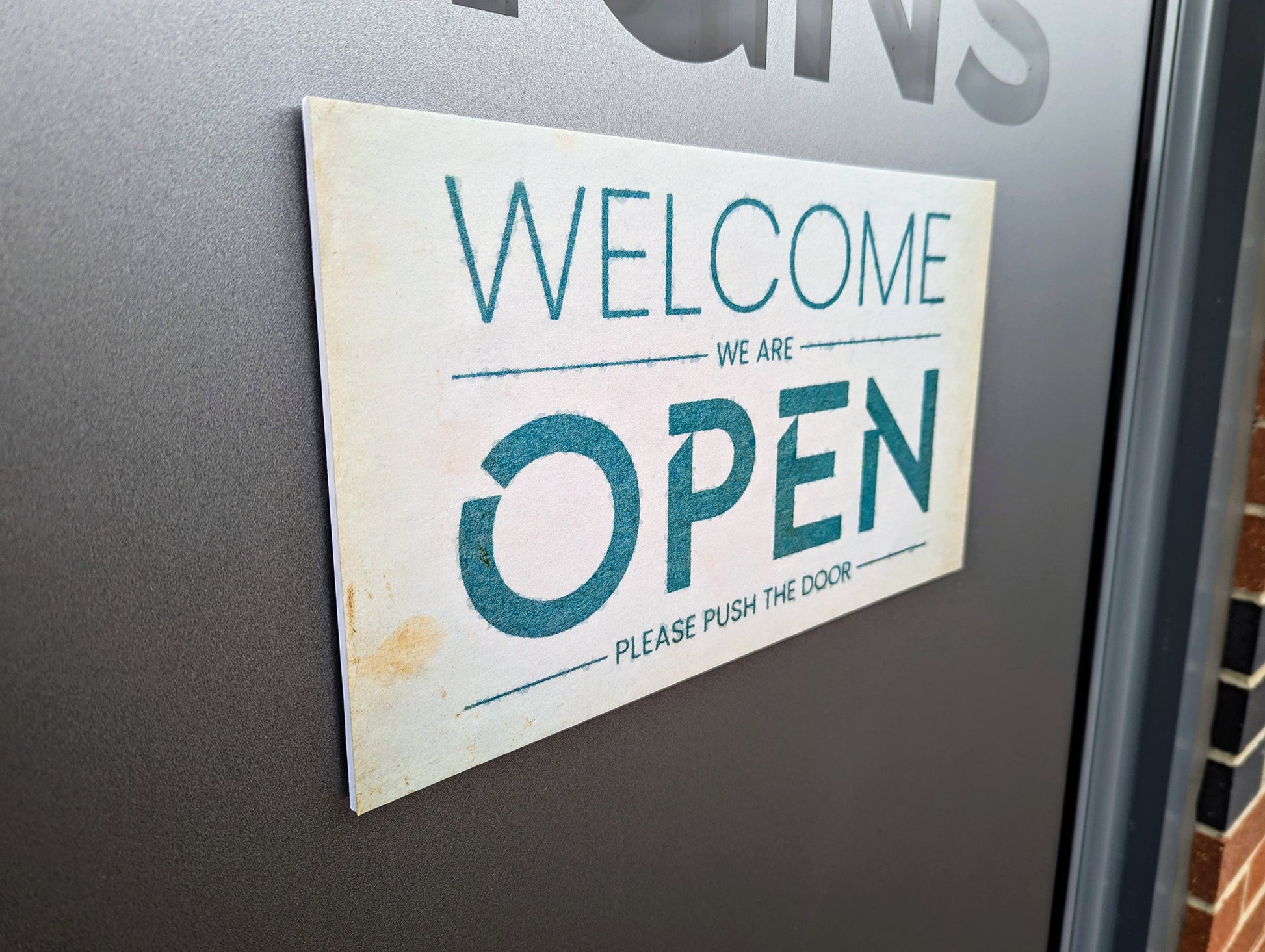 Open sign fixed to glass door with velcro pads. Sign is removable and made from 5mm foamex with print to face.