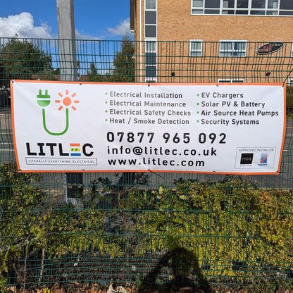 A printed PVC banner hanging from a green metal fence.